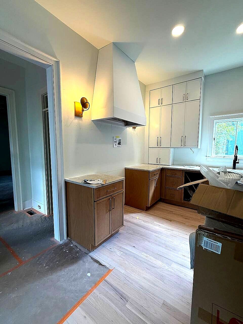 Tapered white range hood installed before the backsplash in a two-tone kitchen