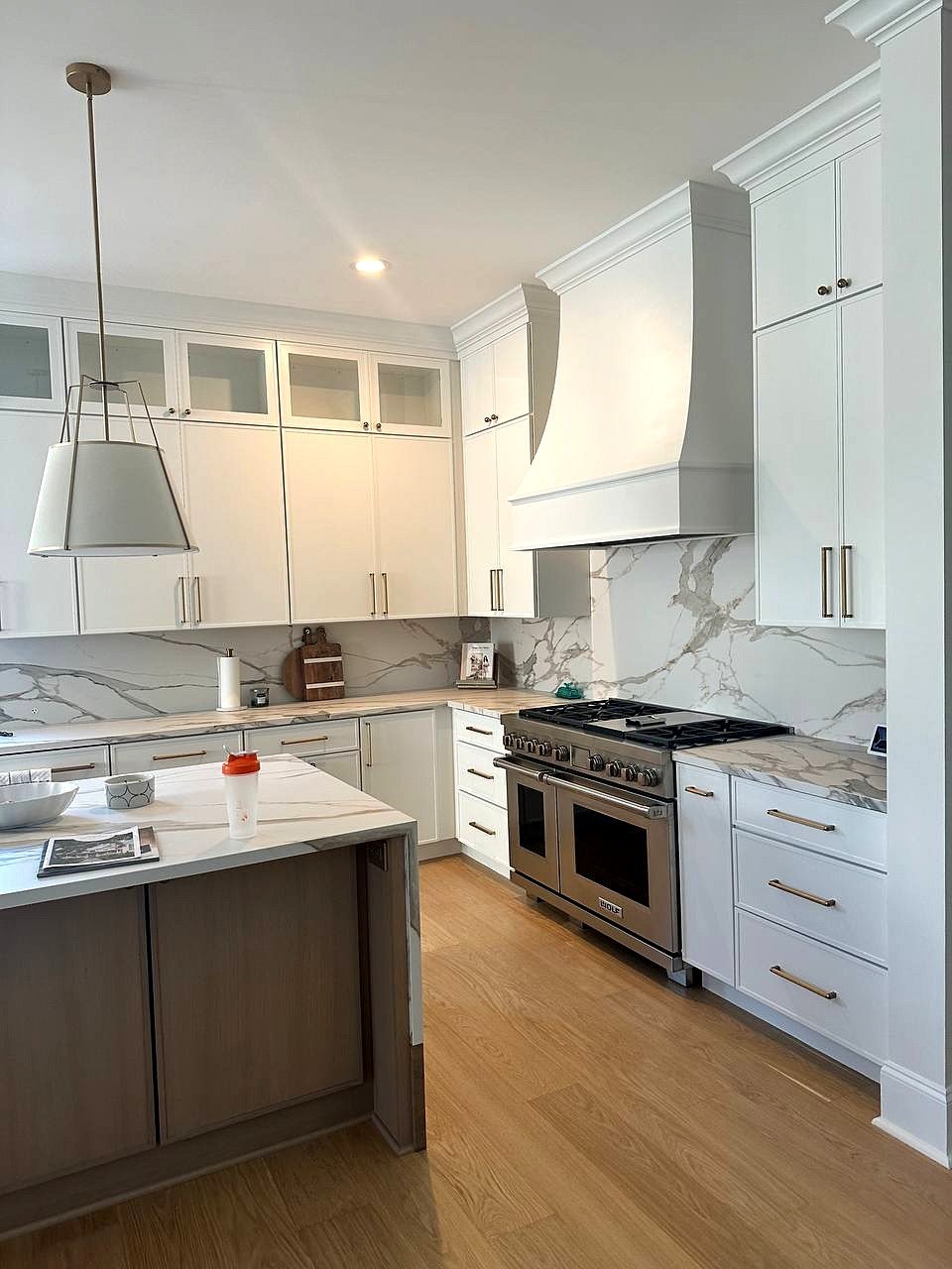 Curved range hood painted to match white shaker cabinets and run into the crown, over a pro-style gas range