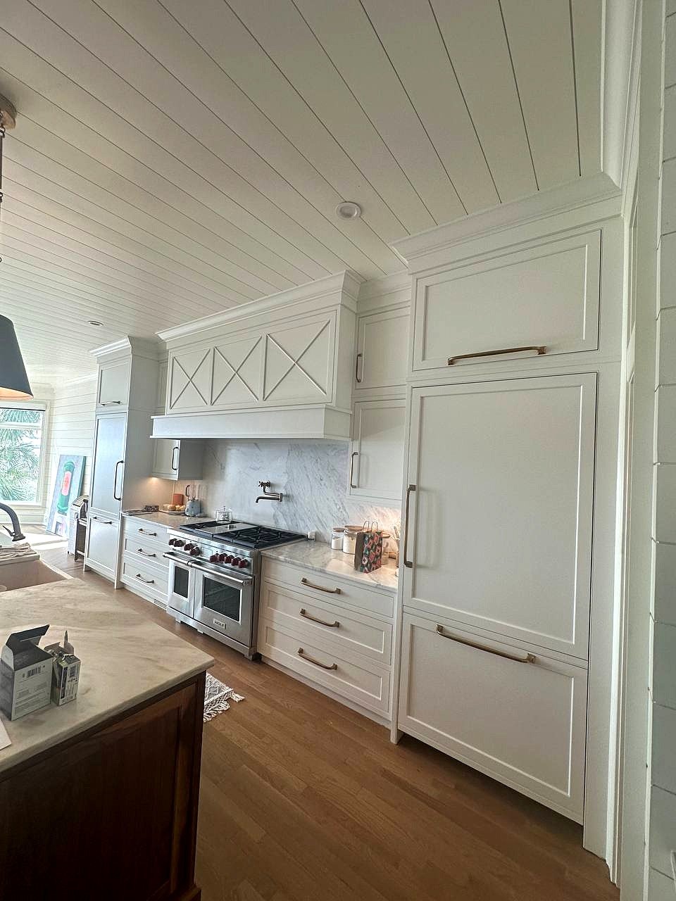 Box range hood with X-panel detail painted white under a shiplap ceiling