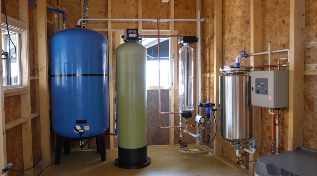 A private well treatment train with pressure tank, iron filter and ultraviolet disinfection chamber